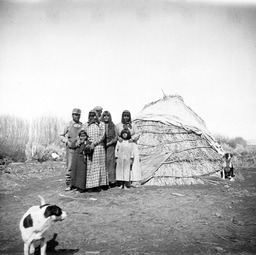 People standing by straw wickiup