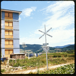 Railroad sign with building and mountains in background
