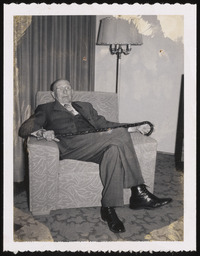 Dr. Church in armchair with cane at 90th birthday party