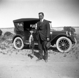 Man holding string of fish by a 1921 Dodge Touring Car at  Pyramid Lake