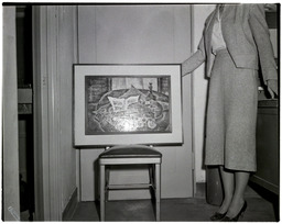 A woman displaying an artwork on a chair, 2