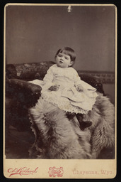 Unidentified baby girl sitting on a fur blanket