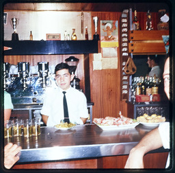 Young man standing behind bar counter