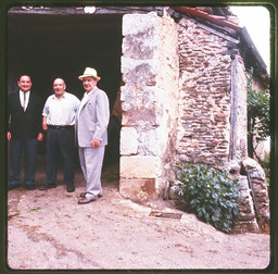 Three men in front of stone building