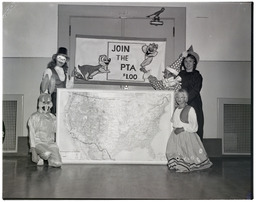 Children in costumes stand before a US map with a Join the PTA sign