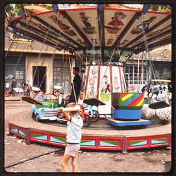 Boy walking in front of a carousel