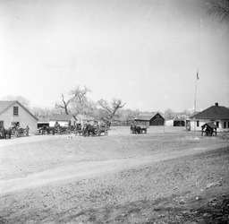 Teams of horses pulling wagons among buildings
