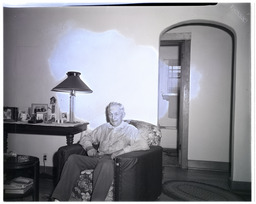 An older man sitting on a chair in a house