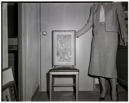 A woman displaying an artwork on a chair, 1