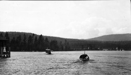 Woman standing on end of pier and two small boats at Lake Tahoe