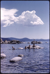 Children swimming and sitting around boulders at Lake Tahoe
