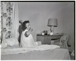 A woman in a nightgown stretches in bed