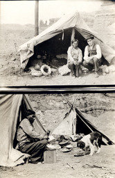 White man and Indian sitting in front of a tent