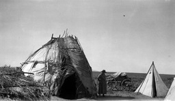 Woman standing by wickiup