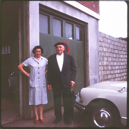 Man and woman standing by car in front of house