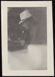 Dr. Church in hat, writing at desk