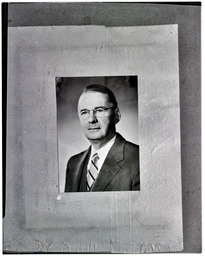 A portrait of a man in a suit and tie and glasses
