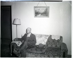 An older man sitting on a sofa in a house