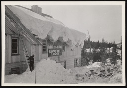 Beacon-Hill Lodge covered with a cornice of snow and a man climbing a ladder