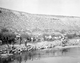 People with wagons and horses beside water