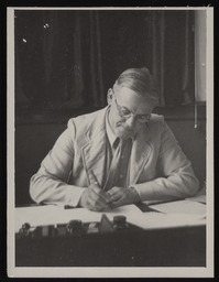 Reginald Titt writing at desk