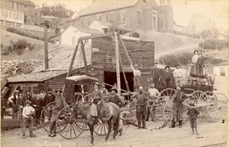 Men, boys, and horses in front of McComb shop