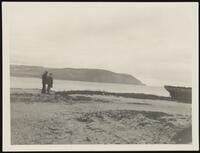 Two men standing on the shore of a bay