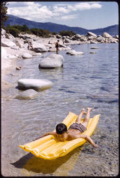 Boy on inflatable raft near boulders at Lake Tahoe shoreline