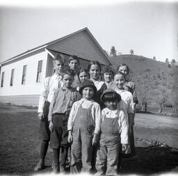 Group of children posed in front of wooden building
