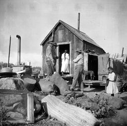 Men standing amid household items