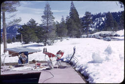 Family at Squaw Valley lodge pool with parked cars in background in snow