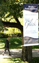 University President Milton Glick walking past a sign with his name, Quad, 2006